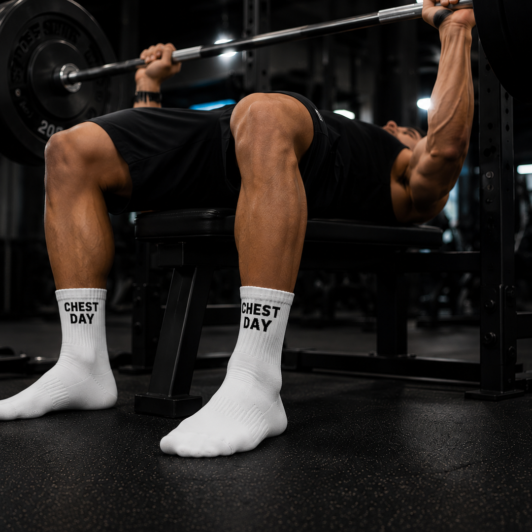 Person lifting weights with 'Chest Day' socks on in a gym setting