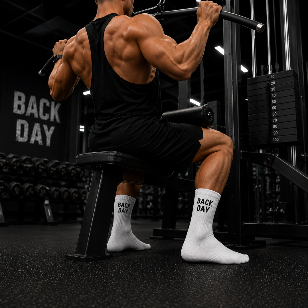 Person working out on a weight machine with 'Back Day' socks on, in a gym setting.